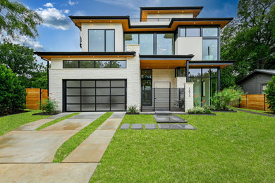 Inspiration for a modern white two-story stone exterior home remodel in Austin with a metal roof and a black roof