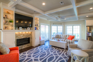 Beach style medium tone wood floor living room photo in Philadelphia with beige walls, a standard fireplace, a stone fireplace and a wall-mounted tv