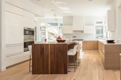 Inspiration for a contemporary eat-in kitchen in Portland with an undermount sink, flat-panel cabinets, light wood cabinets, quartz benchtops, panelled appliances, light hardwood floors and with island.