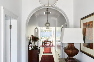 Inspiration for a large hallway in Sydney with white walls, dark hardwood floors and brick walls.