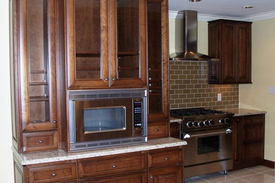 Eat-in kitchen - mid-sized traditional porcelain tile eat-in kitchen idea in Other with an undermount sink, raised-panel cabinets, medium tone wood cabinets, granite countertops, glass tile backsplash, paneled appliances and a peninsula