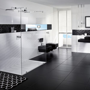 Inspiration for a large modern bathroom in Hamburg with a curbless shower, black tile, stone tile, yellow walls, porcelain floors, black floor, an open shower, wallpaper, wallpaper, black cabinets, a wall-mount toilet, glass benchtops, black benchtops, a single vanity and a floating vanity.