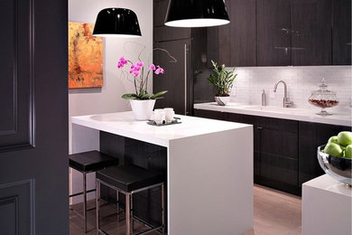 Mid-sized trendy l-shaped light wood floor enclosed kitchen photo in Salt Lake City with an undermount sink, flat-panel cabinets, dark wood cabinets, quartz countertops, white backsplash, glass tile backsplash, paneled appliances and an island