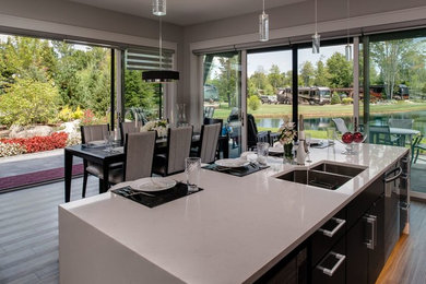 Example of a large trendy galley medium tone wood floor eat-in kitchen design in Other with a double-bowl sink, flat-panel cabinets, black cabinets, quartz countertops, stainless steel appliances and an island