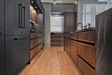 Eat-in kitchen - mid-sized contemporary l-shaped light wood floor and brown floor eat-in kitchen idea in Minneapolis with an undermount sink, recessed-panel cabinets, quartz countertops, metallic backsplash, porcelain backsplash, paneled appliances, an island, black countertops and medium tone wood cabinets