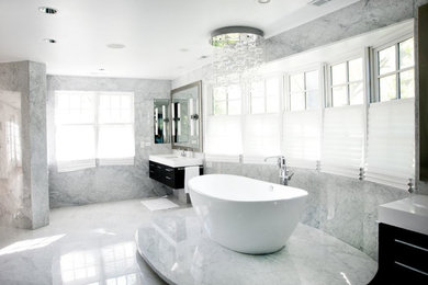 Inspiration for an expansive contemporary master bathroom in Chicago with flat-panel cabinets, black cabinets, a freestanding tub, an alcove shower, stone slab, grey walls, marble floors, an undermount sink and solid surface benchtops.