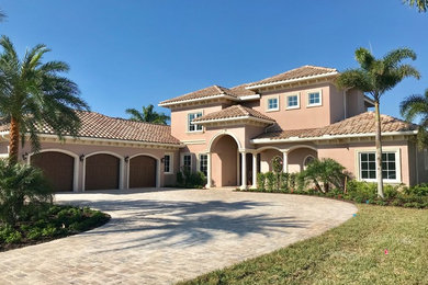 This is an example of a large mediterranean two-storey stucco brown house exterior in Miami with a hip roof and a tile roof.