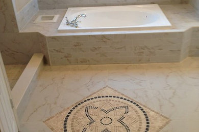 Inspiration for a transitional bathroom in Jacksonville with a drop-in tub, beige tile, stone tile, beige walls and marble floors.