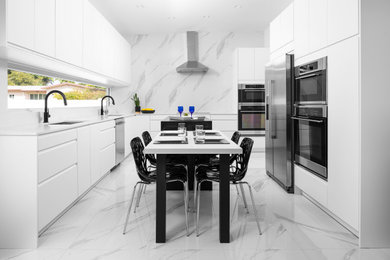 This is an example of a mid-sized contemporary l-shaped eat-in kitchen in Miami with an undermount sink, flat-panel cabinets, white cabinets, quartz benchtops, white splashback, porcelain splashback, stainless steel appliances, porcelain floors, with island, white floor and white benchtop.