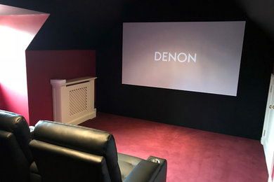 This is an example of a small contemporary enclosed home cinema in Gloucestershire with red walls, carpet, a projector screen and red floors.