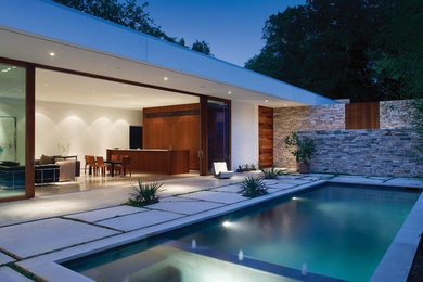 Photo of a large modern backyard rectangular lap pool in Dallas with concrete slab.