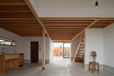 他の地域にある小さなモダンスタイルのおしゃれなLDK (白い壁、コンクリートの床、グレーの床、表し梁、ベージュの天井) の写真