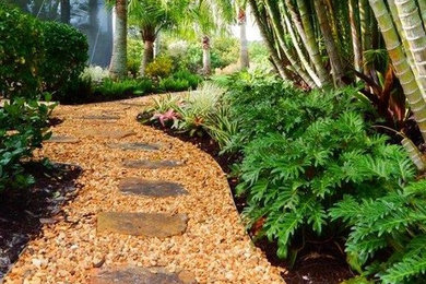 Inspiration for a mid-sized tropical side yard partial sun garden in Tampa with natural stone pavers.