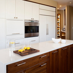 Réalisation d'une grande arrière-cuisine tradition en U avec un évier encastré, un placard à porte shaker, des portes de placard en bois brun, une crédence beige, un électroménager en acier inoxydable, un sol en bois brun, un îlot central, un plan de travail en surface solide et une crédence en carreau briquette.