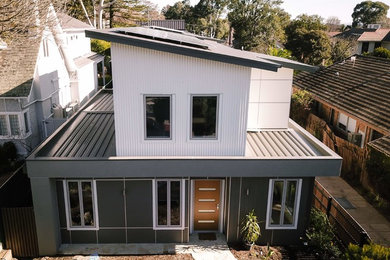 Contemporary two-storey brown townhouse exterior in Melbourne with wood siding, a flat roof and a metal roof.