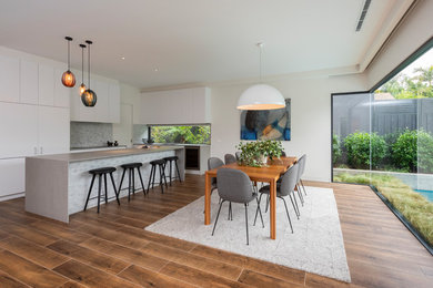 Large contemporary l-shaped eat-in kitchen in Melbourne with brown floor, dark hardwood floors, flat-panel cabinets, an undermount sink, white cabinets, quartz benchtops, multi-coloured splashback, stone tile splashback, stainless steel appliances, multi-coloured benchtop and with island.