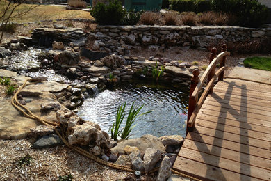 Design ideas for a mid-sized rustic partial sun backyard stone landscaping in Other.