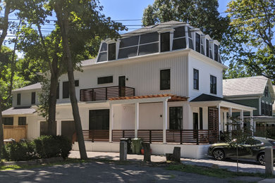 This is an example of a transitional white duplex exterior with wood siding, a black roof and board and batten siding.