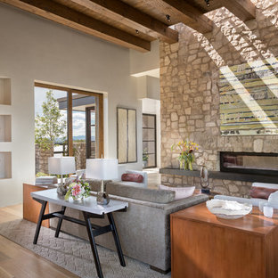 Mittelgroßes, Repräsentatives, Fernseherloses, Offenes Mediterranes Wohnzimmer mit beiger Wandfarbe, Gaskamin, beigem Boden, hellem Holzboden und Kaminsims aus Stein in Albuquerque