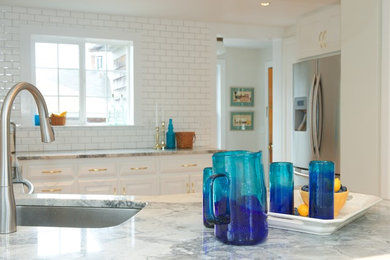 Mid-sized cottage chic u-shaped medium tone wood floor and brown floor eat-in kitchen photo in Boston with an undermount sink, raised-panel cabinets, white cabinets, quartzite countertops, white backsplash, ceramic backsplash, stainless steel appliances and a peninsula