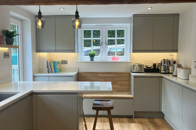 Photo of a small contemporary enclosed kitchen in Berkshire with flat-panel cabinets, grey cabinets, quartz worktops, white splashback, engineered quartz splashback, vinyl flooring, a breakfast bar, white worktops, exposed beams and feature lighting.