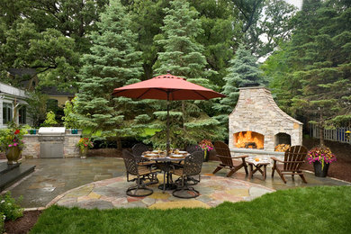 Design ideas for a traditional backyard patio in Minneapolis with an outdoor kitchen and natural stone pavers.
