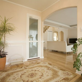 Новый формат декора квартиры: большая узкая прихожая в классическом стиле с розовыми стенами, паркетным полом среднего тона, одностворчатой входной дверью, белой входной дверью и бежевым полом