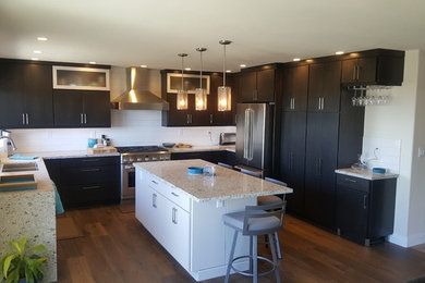 Example of a large trendy u-shaped light wood floor and brown floor eat-in kitchen design in Orange County with an undermount sink, flat-panel cabinets, quartz countertops, white backsplash, porcelain backsplash, stainless steel appliances and an island