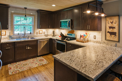 Mid-sized transitional u-shaped light wood floor and brown floor open concept kitchen photo in Other with a drop-in sink, shaker cabinets, gray cabinets, laminate countertops, white backsplash, subway tile backsplash, stainless steel appliances, a peninsula and white countertops