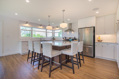 Example of a large transitional u-shaped medium tone wood floor open concept kitchen design in Toronto with a farmhouse sink, shaker cabinets, white cabinets, marble countertops, white backsplash, subway tile backsplash, stainless steel appliances and an island