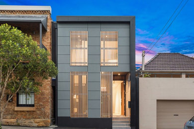 This is an example of a small and gey modern semi-detached house in Sydney with three floors, concrete fibreboard cladding, a flat roof and a metal roof.