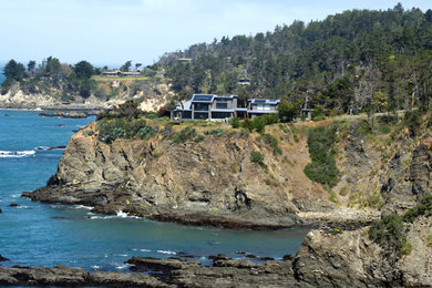 Large beach style gray two-story stone exterior home photo in San Francisco with a metal roof and a gray roof