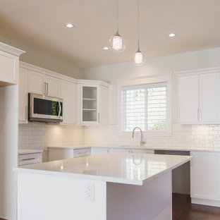 Idéer för att renovera ett gul gult skafferi, med en dubbel diskho, vita skåp, bänkskiva i kvarts, vitt stänkskydd, stänkskydd i keramik, rostfria vitvaror, mörkt trägolv, en köksö, brunt golv och skåp i shakerstil