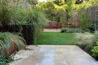 Idée de décoration pour un jardin arrière design avec une exposition partiellement ombragée et des pavés en pierre naturelle.