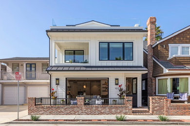 Example of a beach style white three-story mixed siding and board and batten exterior home design in Orange County with a mixed material roof and a black roof