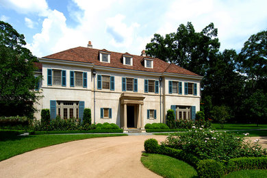 This is an example of a mediterranean stucco beige house exterior in Houston with a tile roof.