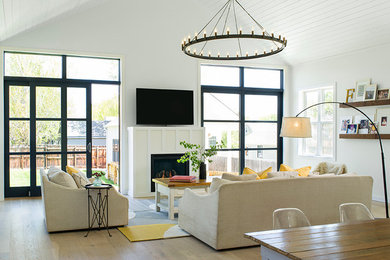 Example of a mid-sized cottage open concept light wood floor living room design in Denver with white walls, a standard fireplace and a wood fireplace surround