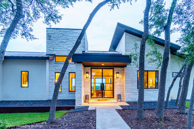 Example of a large minimalist beige one-story mixed siding house exterior design in Austin with a shed roof and a metal roof