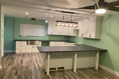 Eat-in kitchen - large contemporary u-shaped vinyl floor and multicolored floor eat-in kitchen idea in Salt Lake City with an undermount sink, shaker cabinets, white cabinets, granite countertops, black backsplash, granite backsplash, a peninsula and black countertops