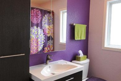Example of a mid-sized trendy vinyl floor bathroom design in Milwaukee with flat-panel cabinets, black cabinets, solid surface countertops and purple walls