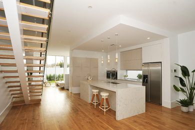 Photo of a contemporary open plan kitchen in Adelaide with a double-bowl sink, flat-panel cabinets, grey cabinets, quartz benchtops, window splashback, stainless steel appliances, plywood floors, with island, multi-coloured floor and multi-coloured benchtop.
