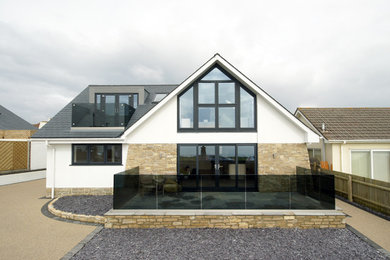 Medium sized and white contemporary two floor detached house in Dorset with stone cladding, a pitched roof and a tiled roof.