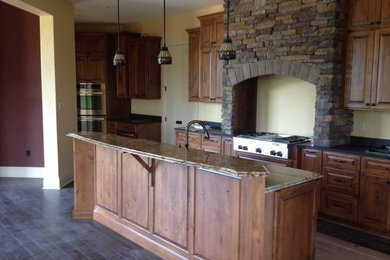 This is an example of a medium sized rustic galley open plan kitchen in Other with a submerged sink, raised-panel cabinets, dark wood cabinets, granite worktops, stainless steel appliances, dark hardwood flooring, an island and brown floors.