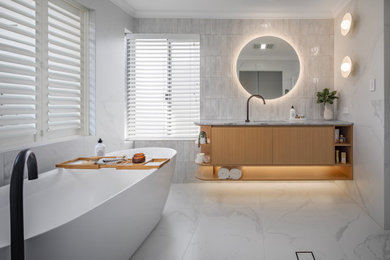 Photo of a mid-sized modern master bathroom in Perth with light wood cabinets, a freestanding tub, white tile, ceramic tile, ceramic floors, an undermount sink, marble benchtops, white floor, white benchtops, a single vanity and a floating vanity.