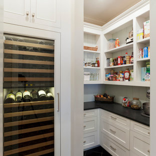 Traditional kitchen pantry designs - Example of a classic kitchen pantry design in Charlotte with recessed-panel cabinets, white cabinets and white backsplash