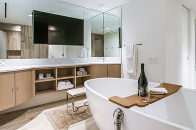 Inspiration for a mid-sized modern master bathroom in Dallas with flat-panel cabinets, light wood cabinets, a freestanding tub, white walls, porcelain floors and an undermount sink.