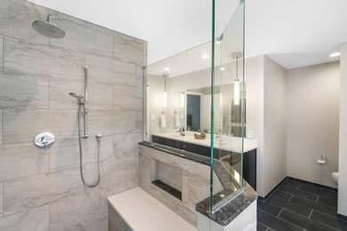 Design ideas for a mid-sized transitional master bathroom in Philadelphia with shaker cabinets, black cabinets, a curbless shower, a two-piece toilet, gray tile, porcelain tile, grey walls, porcelain floors, an undermount sink, engineered quartz benchtops, black floor, an open shower and white benchtops.