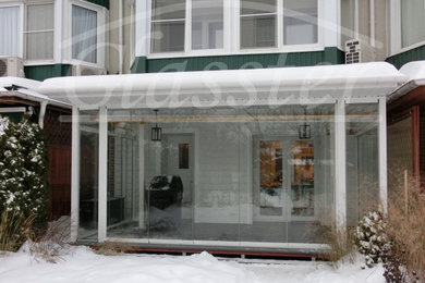 Ejemplo de terraza planta baja clásica grande en patio y anexo de casas con barandilla de vidrio