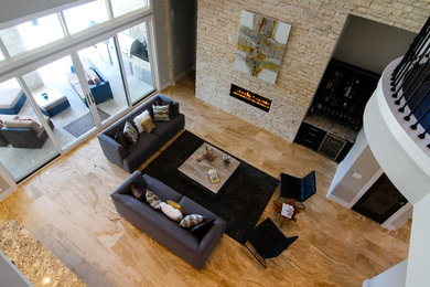 Large trendy enclosed travertine floor living room photo in Austin with a bar, gray walls, a standard fireplace, a stone fireplace and no tv