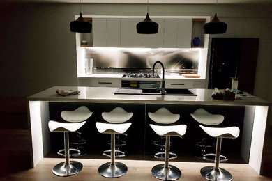 This is an example of an open plan kitchen in Other with glass sheet splashback and with island.